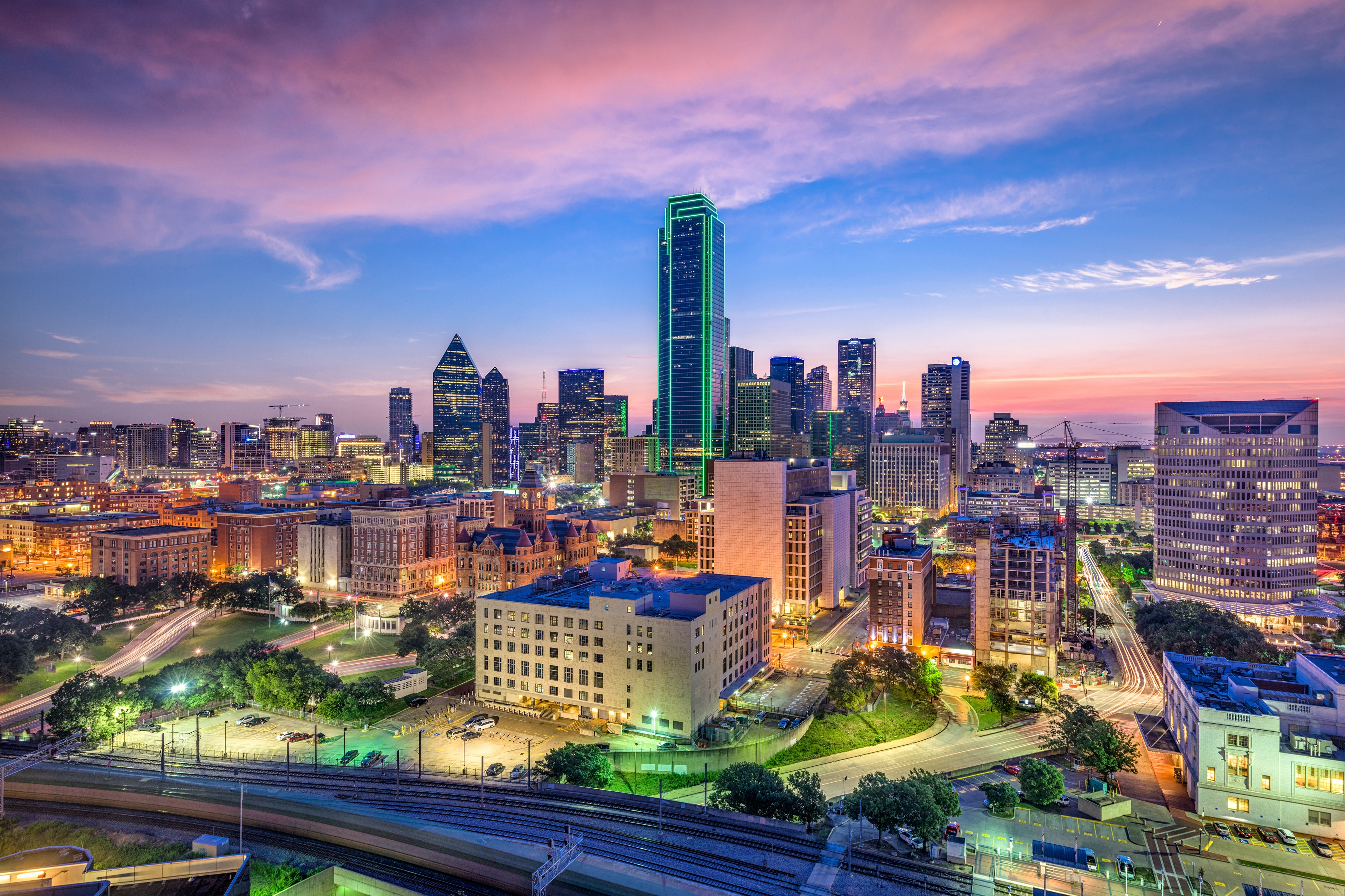 Dallas skyline at sunset with city lights glowing during the holiday season.