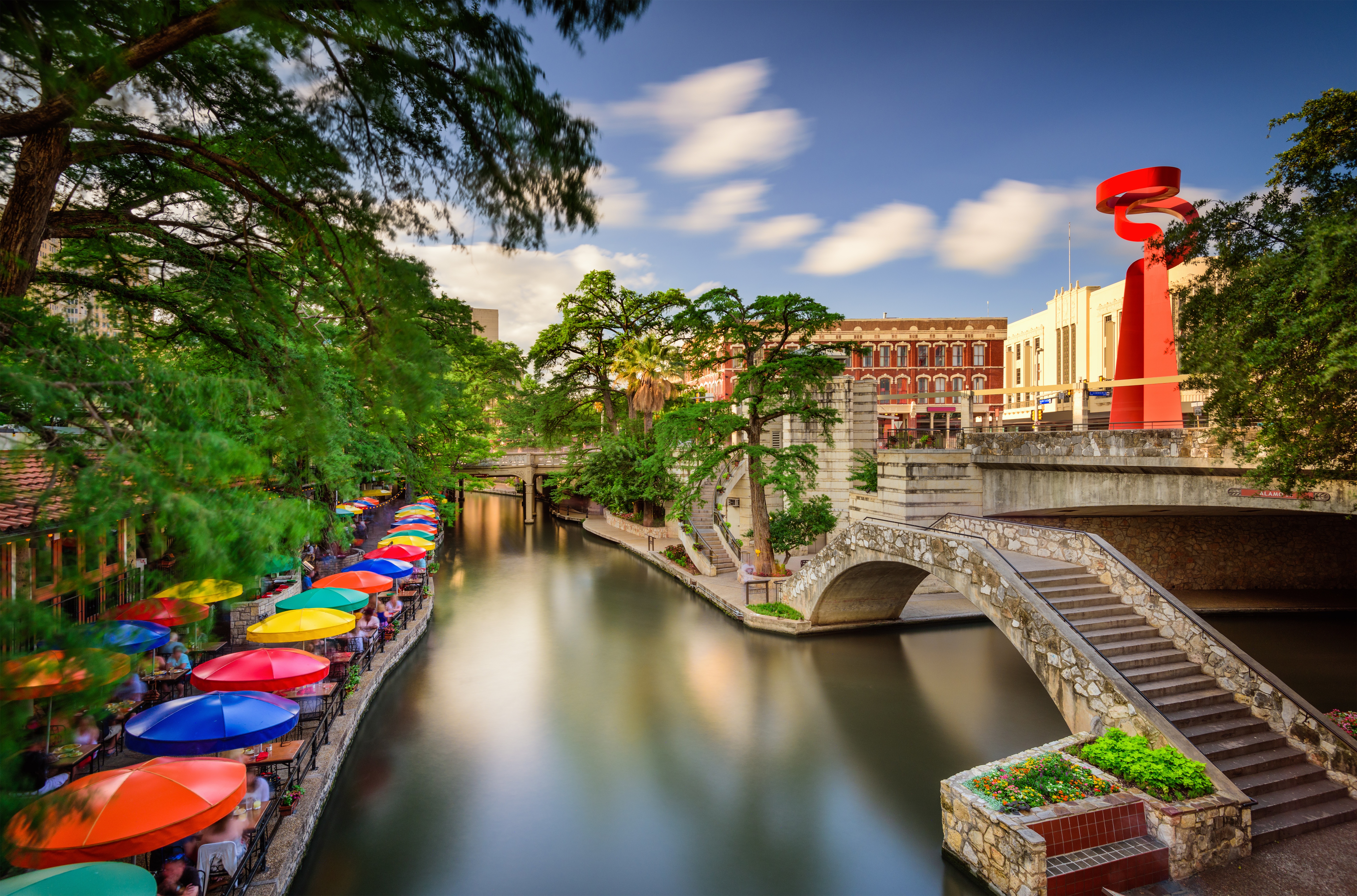 San Antonio River Walk with boats and city buildings at dusk.